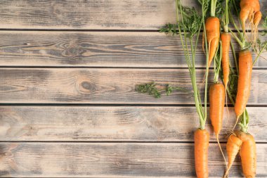 Soluk ahşap masada taze olgun havuçların dikey çizgisi, üst manzara. Çiğ sebzeler sıraya dizildi. Organik gıda ya da sağlıklı diyet konsepti. Nesnelerin konumu. Planking. Metin için yer.