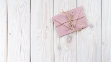 Beyaz ahşap arka planda pembe zarfın 4K görüntüsünü durdurun. Kırmızı karton kalp, Valentine zarfından çıkarılmış. Uzayı kopyala Aşk, sevgililer günü, duyguların itirafı. Üst görünüm