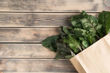 Yeşillik yeşillik ve eko torbada saklanan pancar kökleri, ahşap arka planda bir paket. Ekolojik alışveriş, gıda teslimatı ve organik çiftlik sebze pazarı, market. Üst görünüm, alanı kopyala