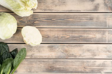 Ahşap arka planda yemyeşil yapraklı lahana dilimleri. Doğal, organik gıda marketi reklamı. Sağlıklı beslenme ve diyet. Çiftlik yemeği. Üst görünüm, şablon, kopyalama alanı