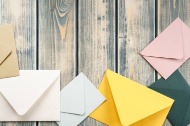 Çok renkli zarflar gri ahşap desenli arka planda rastgele yatar. Uzayı kopyala Mesaj için yer. Üst Manzara. Posta, yazışma, mesaj gönderme, tebrikler.