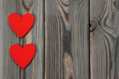 Küçük kırmızı kalpler dans ediyor ve siyah ahşap arka planda daireler çiziyor. Aziz Sevgililer Günü, 14 Şubat aşk kartı selamları. El yapımı hafıza, kalpten gelen bir zanaat. Boşluğu kopyala, üst görünüm