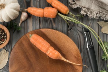 Olgun turuncu havuç ve sebze soyacağı. Düz görüş. Soyulmamış havuç. Mutfak tahtasının kabuğunu kesmek. Yemek ve yemek tarifi için malzemeleri hazırlayın. Sebze ve aromalar..