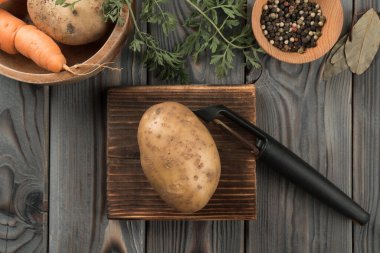 Sebze soyuculu sarı patates soymak. Düz görüş. Soyulmamış taze patates. Mutfak tahtasının kabuğunu kesmek. Yemek için malzemeleri hazırlayın. Sağlıklı yiyecekler. Sebze ve aromalar..