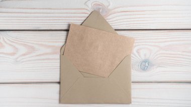 Boş kahverengi geri dönüştürülmüş el işi kağıdın üst görüntüsü gri ahşap masadaki açık el sanatları zarfında katlandı. Mektuplar, postalar, postane, kırtasiye, belge, geri dönüşüm. Düz yat, boşluğu kopyala.