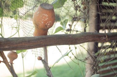 Ahşap çitte baş aşağı asılı eski kil çömlek. El yapımı antika seramik vazo. Kırsal ev eşyası, çanak çömlek, el işi. Kırsal yaşam, kırsal dekor, yemekler. Yaz doğası, yeşil bitkiler.