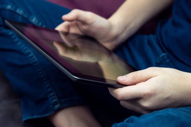 Dijital tablet bilgisayar erkeklerin elinde, yan görüş yakın. Genç adam iş ve oyun için çoklu el bilgisayarı kullanıyor. Modern teknoloji, tablet ellerde, dokunmatik ekran, elektronik.