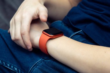 Erkek bileğinde kırmızı stil akıllı saat yakın plan. Genç iş adamı, zaman ve veriye bakmak için boş ekrandaki takılabilir aletlere dokunuyor. Çoklu görev saati, dokunmatik ekran, modern elektronik..