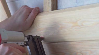 Video, tahta tahta tahta için zımba, çivi ve çivi tabancası kullanarak kesilmiş insan ellerini kapatıyor. Metal çivi ve zımbaları kesmek, ahşap iskelet temelini oluşturur. İnşaat işçisi, inşaat mühendisi.