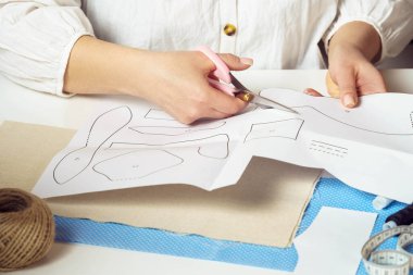 El yapımı, kendin yap, özel ders. Tanımlanamayan kadın terzi elleri farklı şekiller kesiyor, gelecekteki giysiler için kağıttan desenler ve oyuncak dikiş tasarımı projeleri. Tekstil üretimi