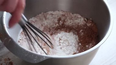 Tanınmayan kadınların karışımının en üst görüntüsü: şeker, çikolata, un ve metal çırpı yuvarlak metal kasede, kek pişirmek için hamur hazırlamak. Şekerleme, ev yapımı tatlı, pasta, yemek..