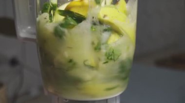 Çalışan elektrik mikserinin taze yeşil smoothie hazırlarken, kivi, limon, elma, yeşillik, salatalık harmanlarken yan görüntüsü. Mutfak eşyaları, sebzeler, sebzeler, vejetaryen meyveler, sağlıklı yiyecekler, yemek pişirme..