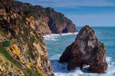 Sahil kıyı şeridi kenarındaki mavi lagün kıyısındaki sarp kayaların yeşil çimlerle kaplı su dağı uçurumlarının manzarası. Yaz, tatil, seyahat, deniz manzarası, turizm, okyanus.