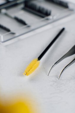 Makyaj sanatçısının kirpik uzatma cımbızı, tarama için fırça açık arkaplanda yatar. Mesaj için yer var. Güzellik anlayışı. Güzellik salonu. Yüz bakımı. Düz çizgi. ÇEVİRİ. 