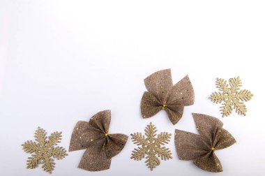 Çuval bezi yaylar altın parıltısı ve beyaz arka planda kar taneleri, Noel tatili dekoru