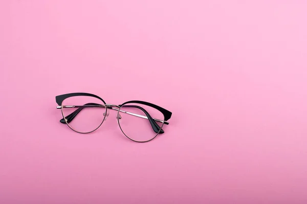 Black frame eyeglasses isolated on pastel pink color background