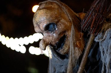 Karanlık bir cadılar bayramı gecesinde süpürge ve canavar suratlı bir cadı.