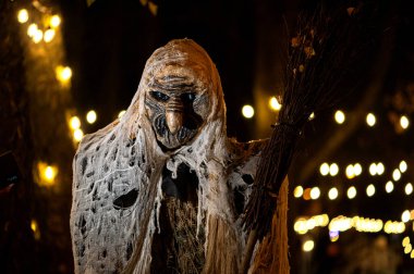 Karanlık bir cadılar bayramı gecesinde süpürge ve canavar suratlı bir cadı.