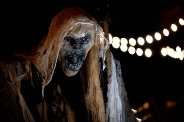 Karanlık bir cadılar bayramı gecesinde süpürge ve canavar suratlı bir cadı.