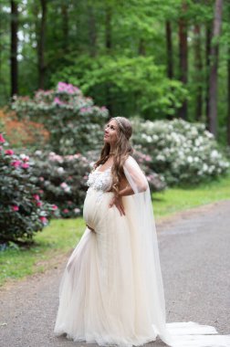 Çiçek açan bir orman parkında romantik hamile bir kadın.