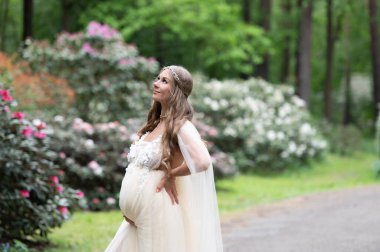 Çiçek açan bir orman parkında romantik hamile bir kadın.