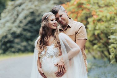 Çiçek bahçesinde kucaklaşan mutlu hamile çift. Çiçek açan rhododendron parkında müstakbel ebeveynler.