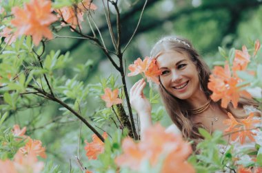 Çiçek açan turuncu rhododendron çiçek dalıyla gülümseyen kadın.