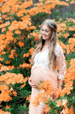 Doğanın çiçek açmasıyla hamile karnını kapat. Hamile kadın rhododendron parkında dinleniyor..