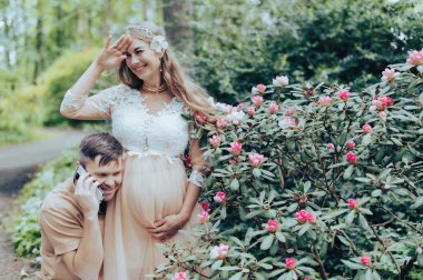 Akıllı telefonlu bir adam hamile karısının karnında bebekle konuşuyor.