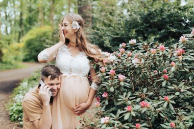 Akıllı telefonlu bir adam hamile karısının karnında bebekle konuşuyor.