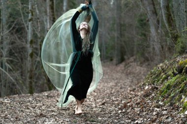 Dişi şaman el değmemiş orman doğasında yürüyor, altın mücevherler, tüylü saçlar