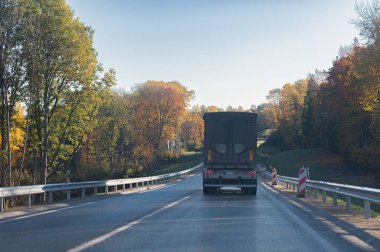 Sonbahar yolundaki bir kamyonun arka görüntüsü.