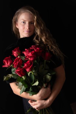 Makyajsız, olgun, doğal bir kadın. Siyah üzerinde kırmızı güller olan güzel bir kadın. Güzel stüdyo portresi. Kırmızı gülleri olan güzel bir model.