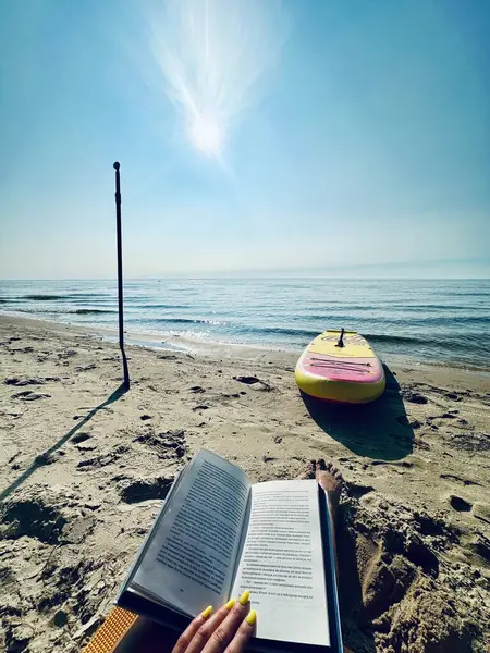 Plajda kitap okuyan bir kadın.