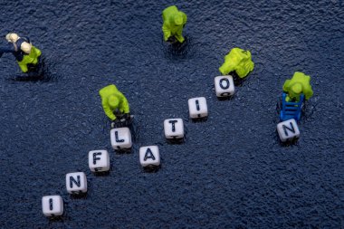 Yüksek enflasyon felaketi konsepti, malların ve hizmetlerin fiyat seviyelerinin artması son aylarda ekonomide küçük itfaiyeci figürünün siyah arka planda tehlikeli madde giysisi ile birlikte