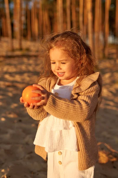 Una Linda Niña Con Vestido Suéter Punto Sosteniendo Una Naranja — Foto de Stock