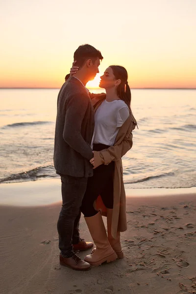 日没時に海の近くの砂浜に抱きつく愛の若いカップル 週末にロマンチックな時間を過ごす — ストック写真