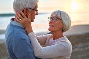 Birbirine aşık yaşlı ve zeki bir çift kumsalda romantik bir şekilde vakit geçirir, birbirlerine nazikçe sarılırlar..