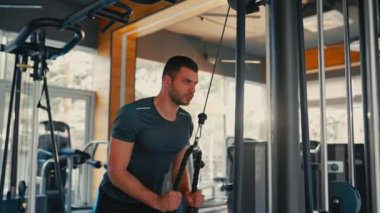 Spor giyimli beyaz kaslı adam spor salonunda trx süspansiyonlu antrenman yapıyor. Spor ve eğlence kavramı..