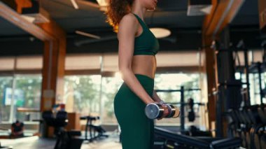 Spor kıyafetli kızıl saçlı, zayıf kadın spor salonunda dambıllarla egzersiz yapıyor. Spor ve eğlence kavramı..