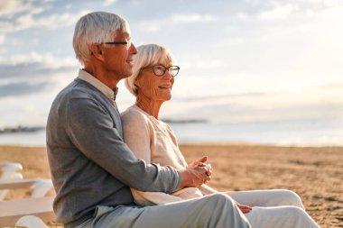 Yaşlı, zeki, gri saçlı, aşık bir çift deniz kıyısındaki bir güneş pansiyonunda oturmuş deniz manzarasına bakarken romantik vakit geçiriyorlar..