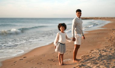 Afrika kökenli Amerikalı bir aile deniz kenarındaki kumlu sahilde eğleniyor. Ağabeyi beyaz elbiseli şirin kız kardeşiyle el ele tutuşan deniz manzarasına bakıyor..