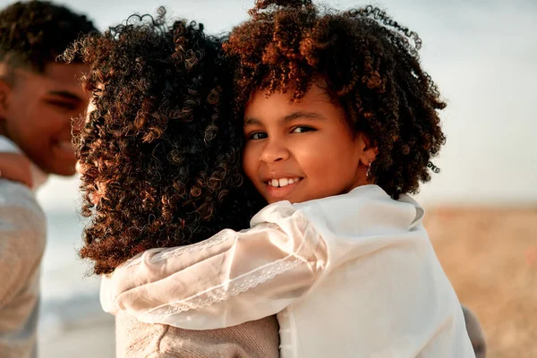 アフリカ系アメリカ人女性お母さんとともに彼女の可愛いです娘とともにAfro Curls立っています巨大上の海岸で夜明けに彼らの週末 — ストック写真