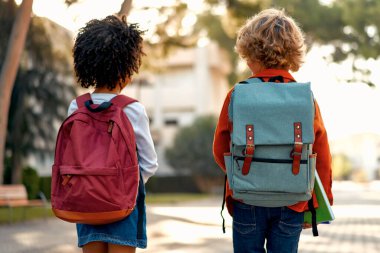 Okul çantaları ve ellerinde not defterleriyle mutlu zeki çocuklar okula koşuşturuyorlar. Okula dönelim. Okuldan sonra bir Afrikalı Amerikalı kız ve sınıf arkadaşı sokakta yürüyorlar..