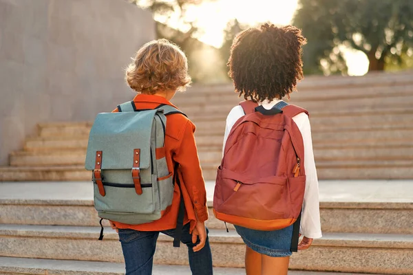 快乐聪明的孩子们背着书包奔向学校 奔上了楼梯 回学校去一个非裔美国女学生和她的同学放学后沿街走着 — 图库照片
