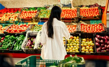 Young pretty asian woman in white shirt choosing groceries in fresh vegetables and fruits store. Healthy food concept. clipart