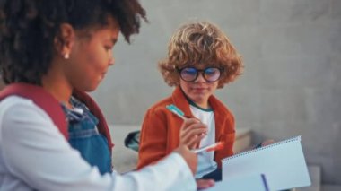 Okulun yanındaki merdivenlerde otururken ödevlerini birlikte yapan zeki çocuklar. Okula dönelim. Gözlüklü beyaz çocukla birlikte ders çalışan Afrikalı Amerikalı bir kız..