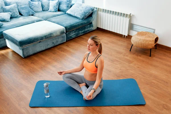 一名穿着运动服的年轻孕妇坐在客厅的橡胶垫子上做运动或瑜伽 怀孕期间的运动 — 图库照片