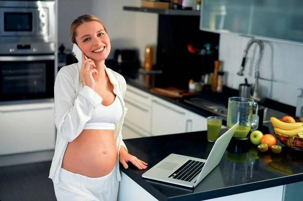 Una Joven Embarazada Cocina Trabajando Portátil Hablando Por Teléfono Mesa —  Fotos de Stock