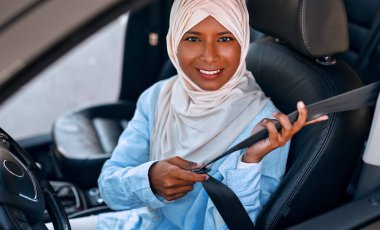 Bir arabanın direksiyonunda oturan tesettürlü genç Müslüman kadın. Bir araba alıp kiralamak. Seyahat ve eğlence..